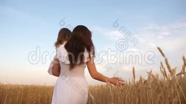 幸福的家庭观念。 母亲带着一个孩子在一片小麦的田野里散步。 妈妈和小女儿在一片田野上玩耍